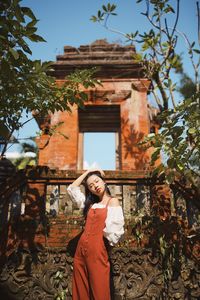 Woman standing by plants against building