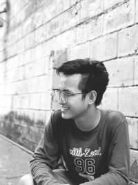 Mid adult man sitting against brick wall
