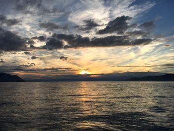 Scenic view of sea against dramatic sky during sunset