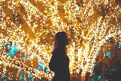 Rear view of man standing on illuminated tree