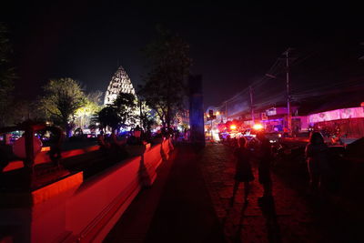 People on illuminated buildings in city at night