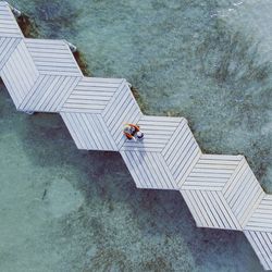 Directly above shot of woman with son sitting on pier over sea