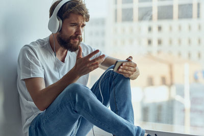 Young man talking on video call sitting by window