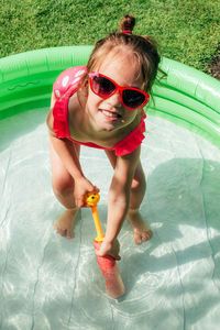 Portrait of cute girl in baby pool playing with holi toy