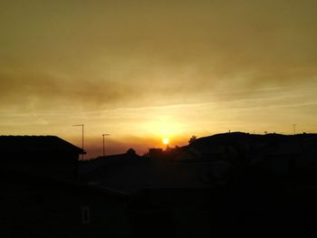 Silhouette houses against sky during sunset