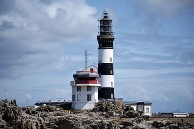 Low angle view of lighthouse by building against sky