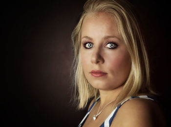 Close-up portrait of a beautiful young woman over black background