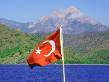 Red flag on lake against mountain range