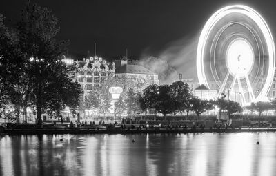 Illuminated city by river at night