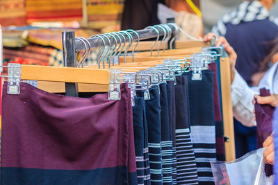 Cropped image of person choosing clothes at store