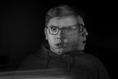 Digital composite image of young man wearing eyeglasses against black background