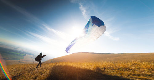 Paraglider with a blue parachute takes off. a man takes off and lands on a yellow field. a man