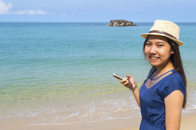 Portrait of smiling young woman standing on beach