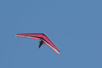 Low angle view of person paragliding against clear blue sky