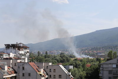 High angle view of smoke emitting from illuminated city against sky