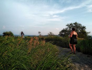 Mother with daughter walking on land against sky