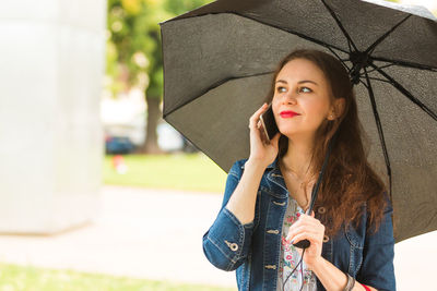 Beautiful woman with umbrella talking on mobile phone