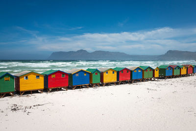 Famous colorful beach houses in muizenberg near cape town, south africa against blue sky with clouds
