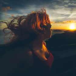 Young woman with tousled hair looking at sunset