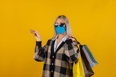 Woman wearing safety gauze mask for prevention from coronavirus, with bags and credit card in hand