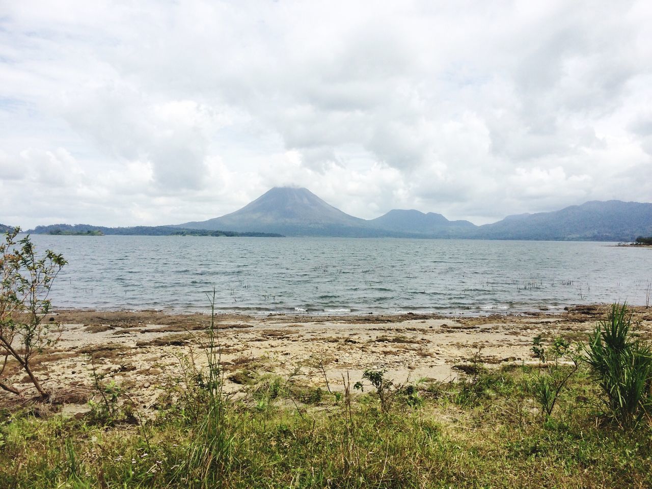 mountain, sky, tranquil scene, mountain range, tranquility, scenics, water, beauty in nature, cloud - sky, grass, cloudy, nature, cloud, landscape, lake, idyllic, sea, non-urban scene, plant, day