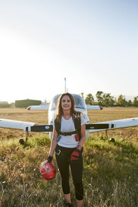 Young female skydiver in an airfield with a plane behind her