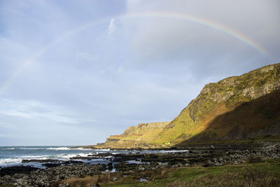 Scenic view of sea against rainbow in sky