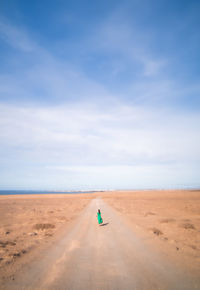 Mid distance view of woman walking on road at desert