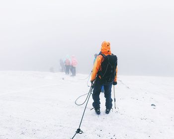 People walking on snow covered landscape during foggy weather