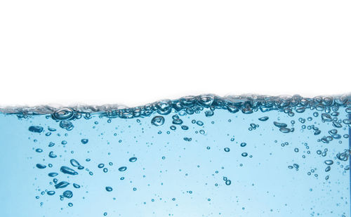 Close-up of water drops on glass against white background
