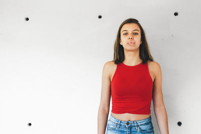 Portrait of a beautiful young woman standing against wall