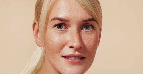 Close-up portrait of young woman against pink background