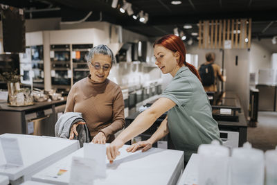 Saleswoman advising female customer in buying appliance at electronics store