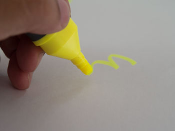 Close-up of hand holding yellow leaf over white background