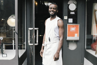 Portrait of happy shop owner standing at entrance