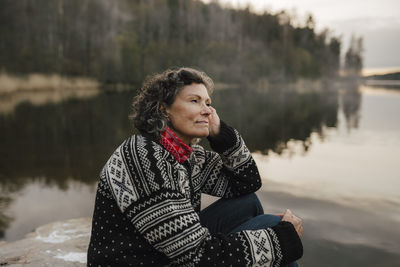 Caucasian female hiker contemplating while sitting by lake