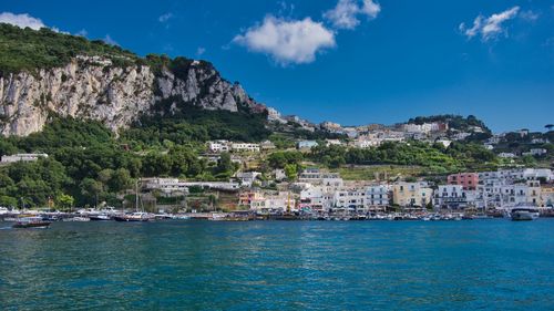 Scenic view of sea by townscape against sky
