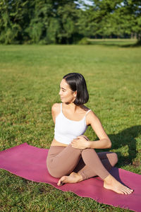 Side view of woman sitting on field