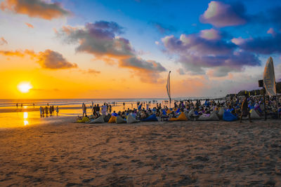 People at beach against sky during sunset