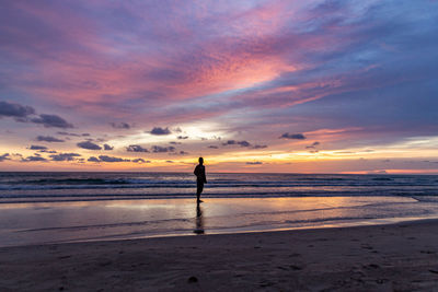 Silhouette  woman standing on beach against sky during sunset