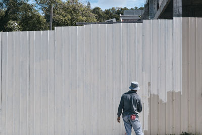 Rear view of man painting wall outdoors