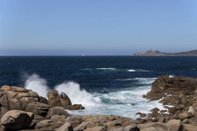 Scenic view of sea  and rocky coastline against clear sky