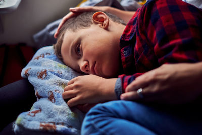 Cute boy lying on mother lap at home