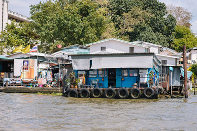 Houses by river against buildings in city