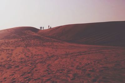 Scenic view of people atop sand dunes