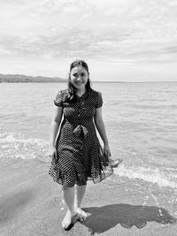 Portrait of woman standing on beach against sea