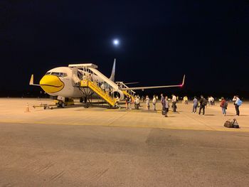 People at airport runway against sky at night