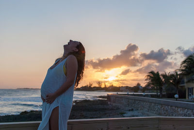 Portrait of smiling pregnant woman standing against sky