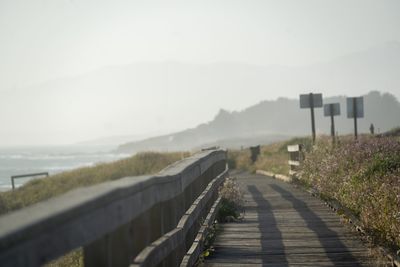 Footpath leading towards mountain against sky