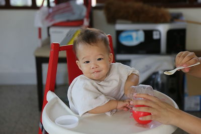 Cropped hands of parent feeding baby boy at table